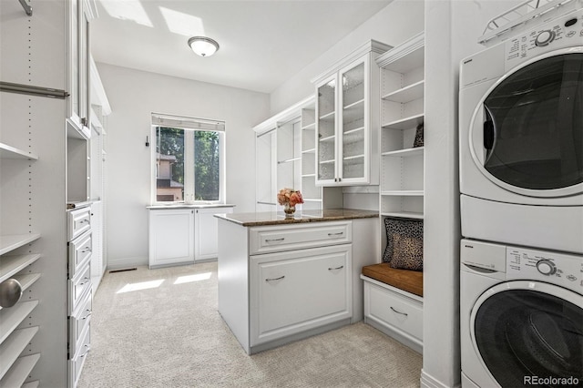 13962 W 76th Ln, Arvada, CO 80005 - laundry area with stacked washer and clothes dryer, light carpet, and cabinet space