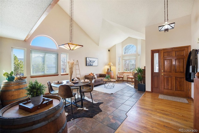 entrance foyer featuring a textured ceiling, high vaulted ceiling, and wood finished floors