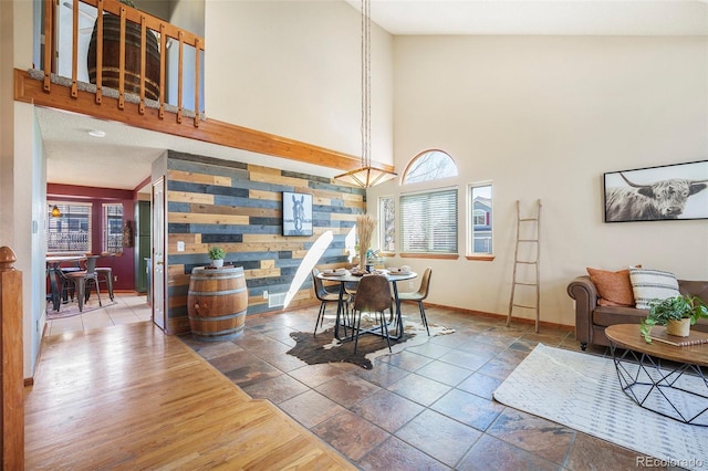 dining area with a towering ceiling, an accent wall, and baseboards