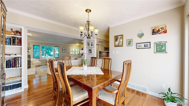 dining space featuring a notable chandelier, crown molding, and wood-type flooring