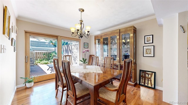 dining area featuring crown molding, wood-type flooring, and an inviting chandelier