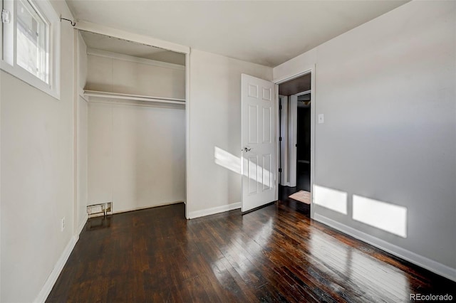 unfurnished bedroom with a closet and dark wood-type flooring