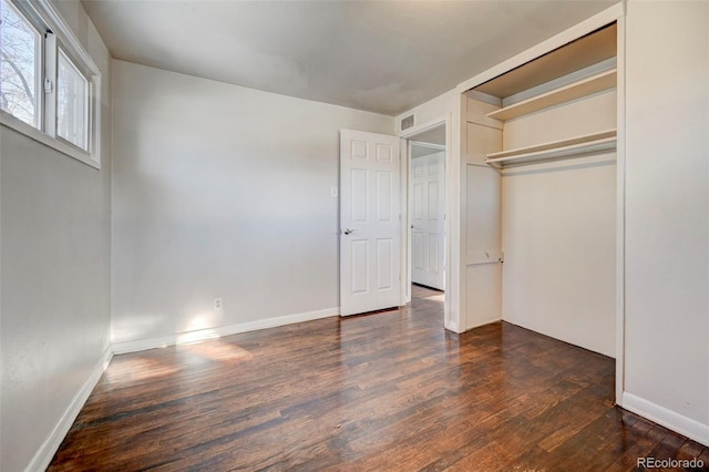 unfurnished bedroom featuring a closet and dark wood-type flooring