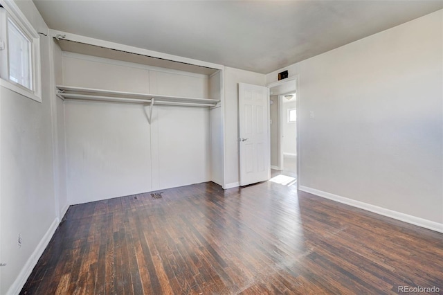 unfurnished bedroom with dark wood-type flooring and a closet