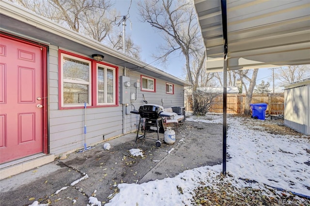 snow covered patio featuring grilling area and central air condition unit