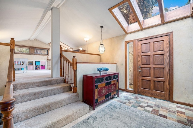 entrance foyer with stairs, a textured wall, baseboards, and lofted ceiling with skylight