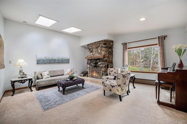 carpeted living room with a skylight, baseboards, and a fireplace