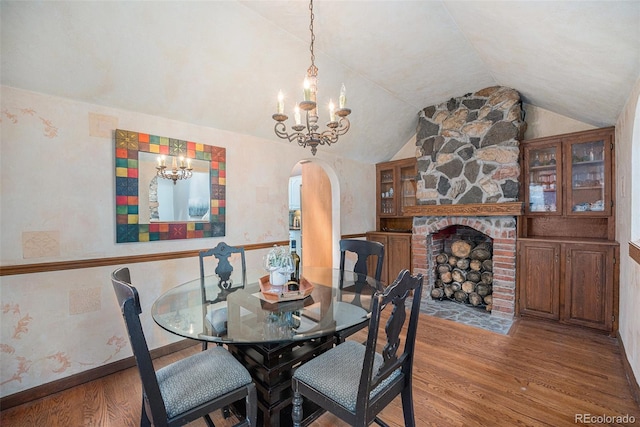 dining room featuring arched walkways, lofted ceiling, wood finished floors, and a chandelier