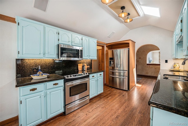 kitchen with blue cabinetry, tasteful backsplash, wood finished floors, a sink, and stainless steel appliances