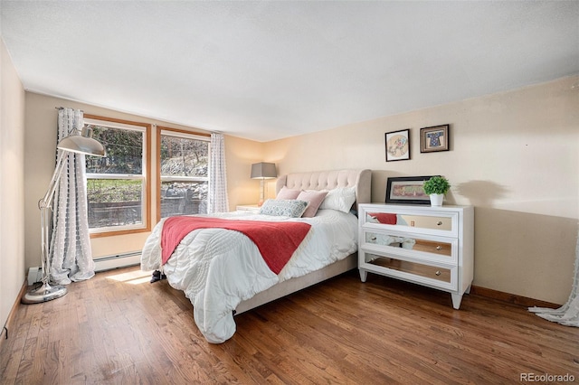 bedroom featuring baseboards, a baseboard heating unit, and wood finished floors