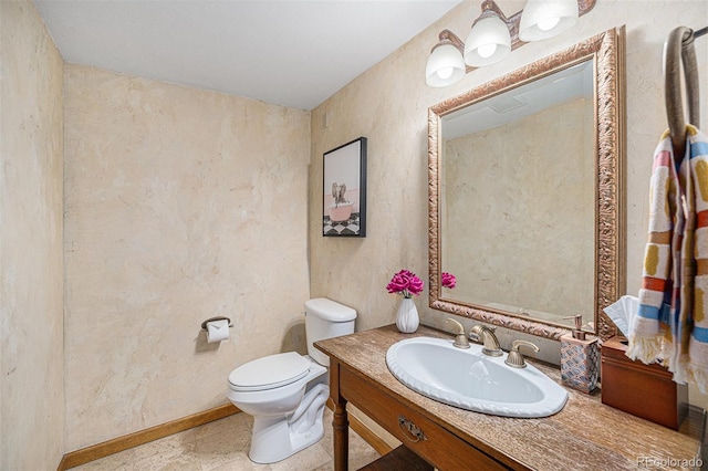 half bath with vanity, baseboards, and toilet