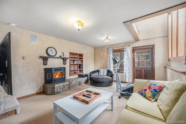 living area featuring carpet floors, baseboards, visible vents, and a wood stove