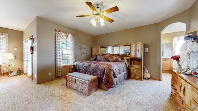 bedroom with ceiling fan, light carpet, and ensuite bathroom