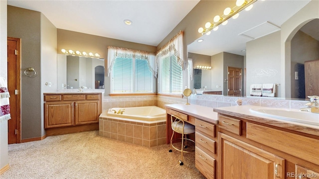 bathroom with tiled tub and vanity