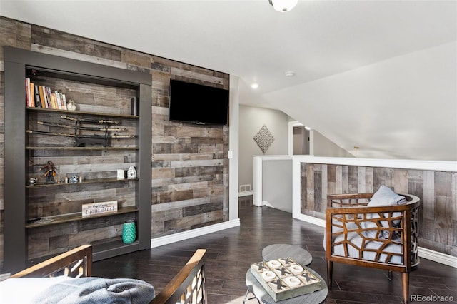 interior space with visible vents, wood finished floors, baseboards, wood walls, and lofted ceiling