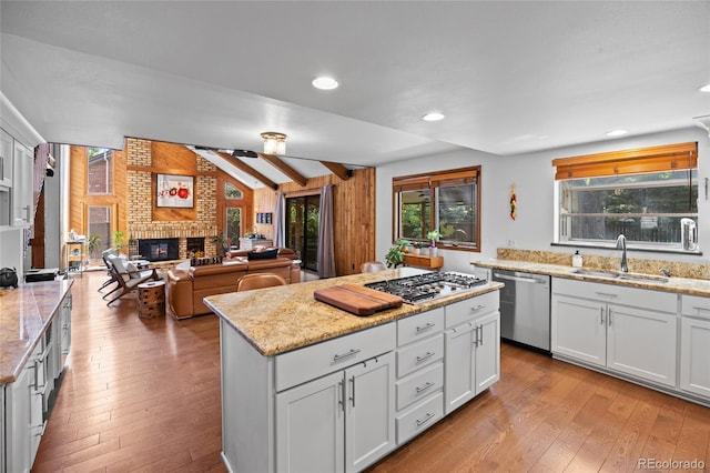 10886 E Crestline Cir, Englewood, CO 80111 - kitchen with appliances with stainless steel finishes, light wood-style floors, a fireplace, a center island, and recessed lighting