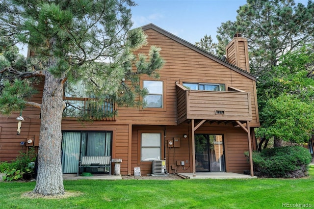 rear view of property featuring a yard, central AC, and a balcony