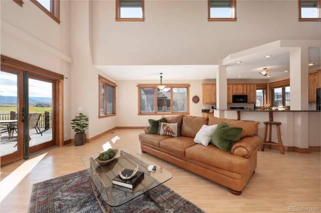 living room featuring a mountain view, light hardwood / wood-style flooring, french doors, and a high ceiling