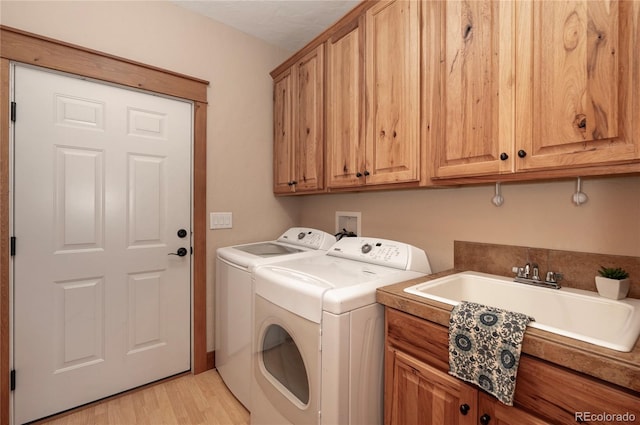 washroom featuring light wood-type flooring, cabinets, sink, and separate washer and dryer