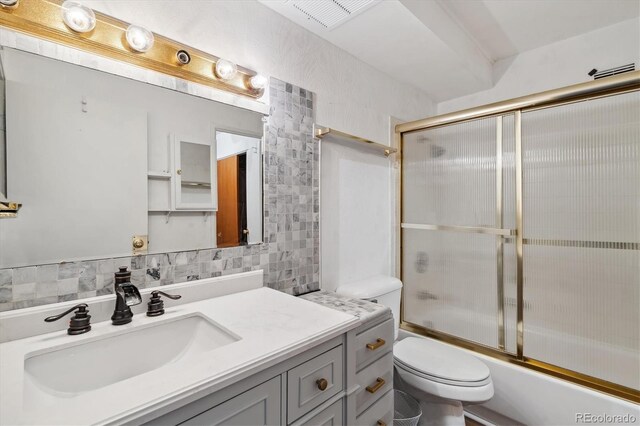 full bathroom featuring enclosed tub / shower combo, toilet, decorative backsplash, and vanity