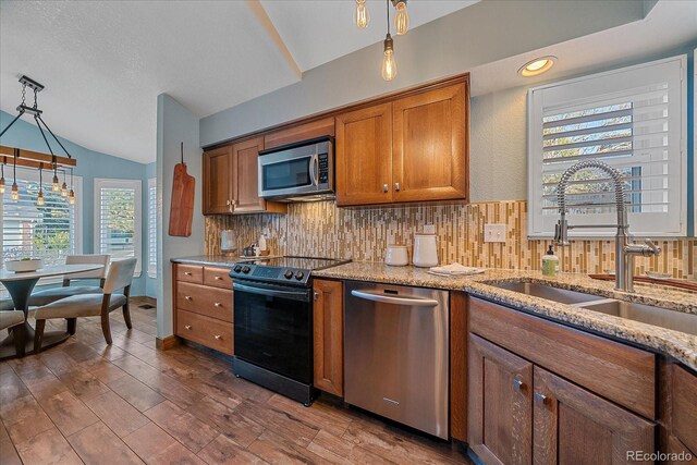 kitchen with a sink, backsplash, stainless steel appliances, brown cabinetry, and lofted ceiling