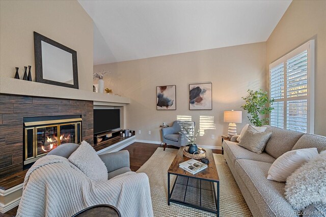 living room with a glass covered fireplace, baseboards, lofted ceiling, and wood finished floors