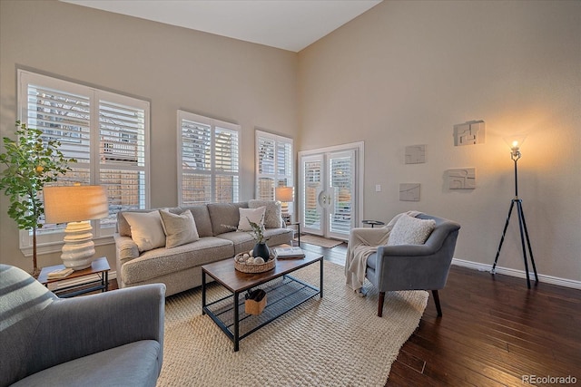 living area with a high ceiling, baseboards, and hardwood / wood-style flooring