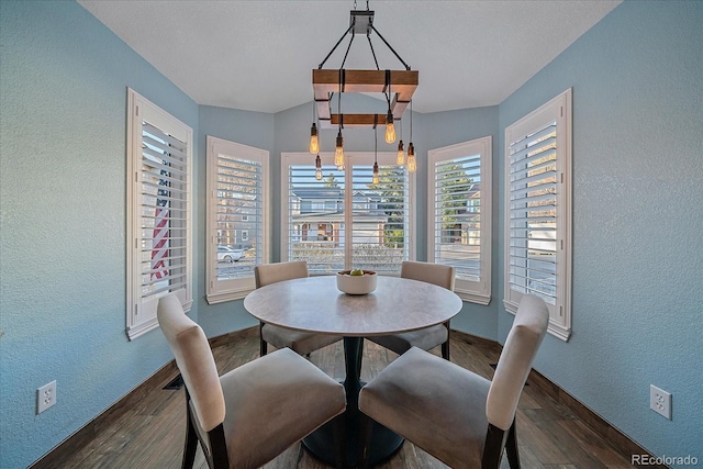 dining area with dark wood-type flooring, baseboards, and a textured wall