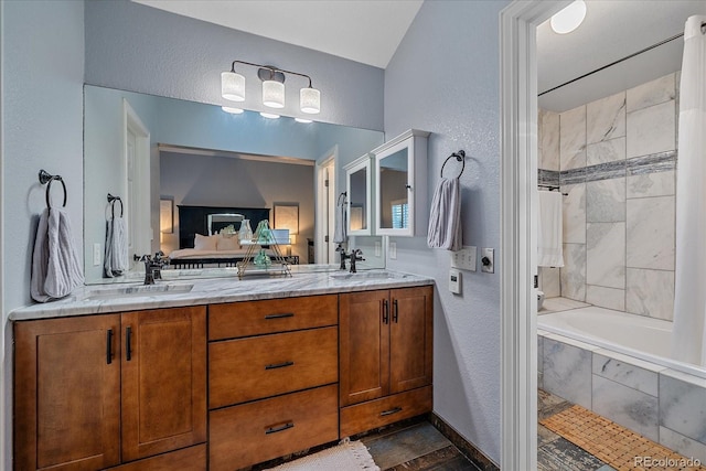 full bath with double vanity, tiled shower / bath combo, a textured wall, and a sink