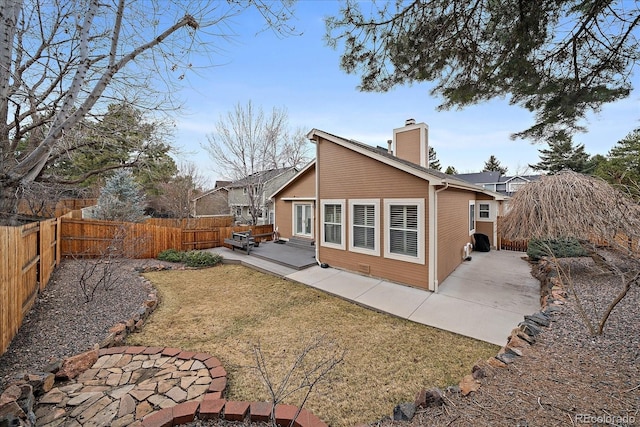 back of property with a yard, a fenced backyard, a chimney, entry steps, and a patio area