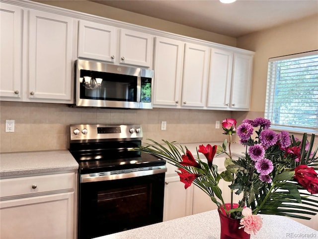 4788 Laurelglen Ln, Highlands Ranch, CO 80130 - kitchen with stainless steel microwave, range with electric cooktop, light countertops, white cabinets, and tasteful backsplash