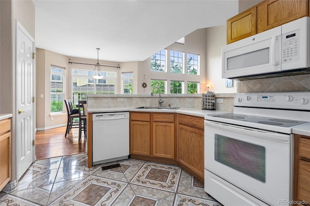 3000 E 112th Ave Unit 86, Northglenn, CO 80233 - kitchen featuring white appliances, a sink, a peninsula, light countertops, and tasteful backsplash
