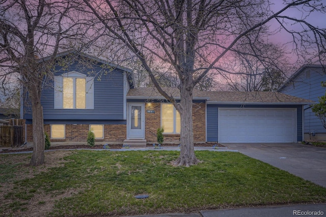 tri-level home featuring an attached garage, concrete driveway, a front lawn, brick siding, and entry steps