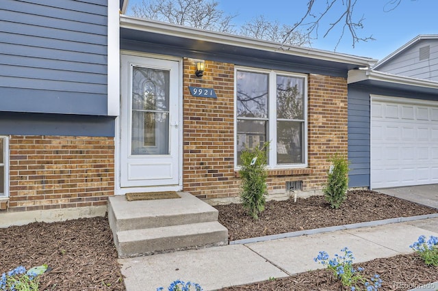 entrance to property with a garage and brick siding