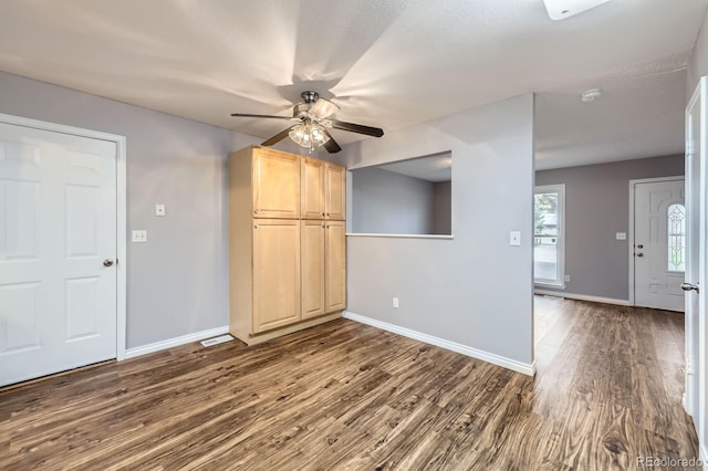 interior space with dark wood-style flooring, baseboards, a ceiling fan, and visible vents
