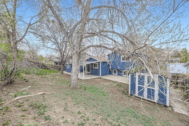 view of yard featuring a patio, an outbuilding, fence, and a storage unit