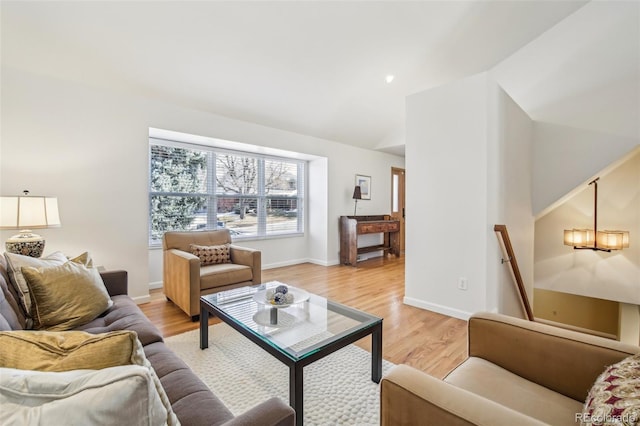 living room featuring light wood-style floors, vaulted ceiling, and baseboards