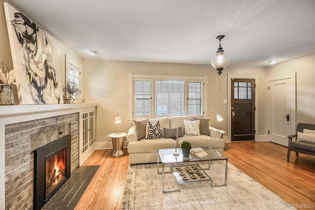 living area featuring a fireplace, wood finished floors, and baseboards