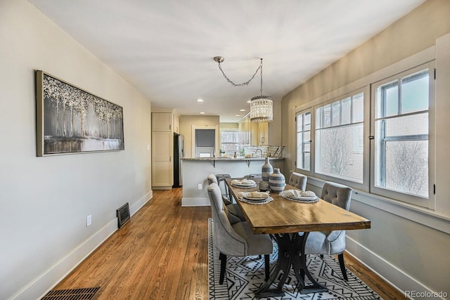 dining space featuring baseboards, wood finished floors, and recessed lighting