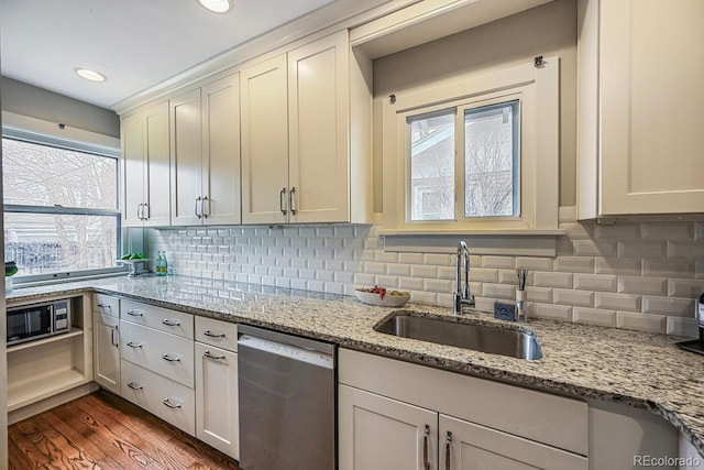 kitchen with stainless steel appliances, a sink, backsplash, and dark wood-style floors