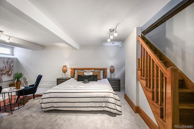 carpeted bedroom with a textured ceiling, beamed ceiling, rail lighting, and baseboards