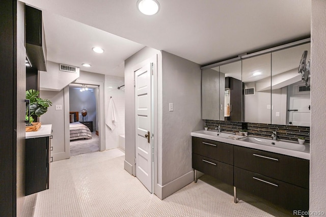 full bathroom with ensuite bathroom, double vanity, a sink, and visible vents