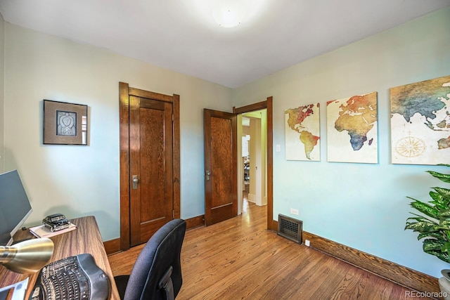 office space with light wood-style floors, baseboards, and visible vents