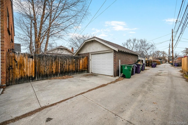 detached garage featuring driveway and fence