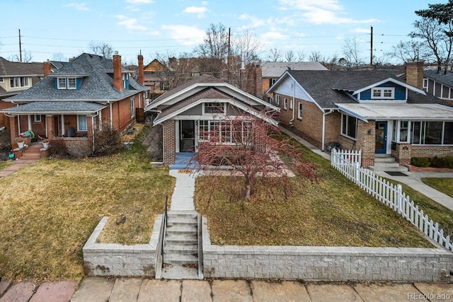 bungalow-style home featuring a front lawn, a residential view, fence, and brick siding