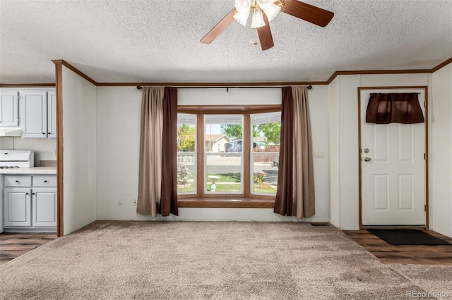 unfurnished living room featuring carpet floors, crown molding, a ceiling fan, and a textured ceiling