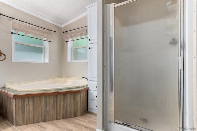 bathroom featuring crown molding, a stall shower, wood finished floors, a bath, and a textured ceiling