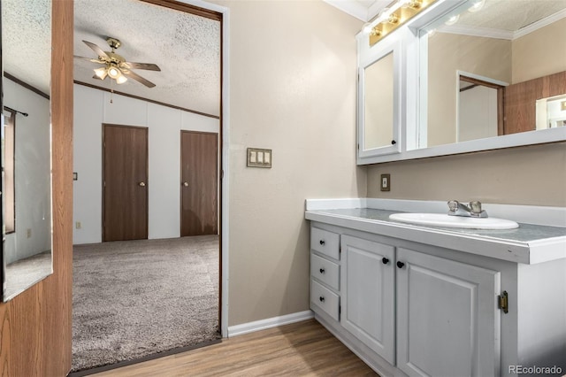 bathroom featuring ornamental molding, a ceiling fan, vanity, a textured ceiling, and wood finished floors