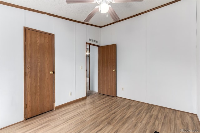 unfurnished bedroom featuring wood finished floors, ornamental molding, a ceiling fan, and a textured ceiling