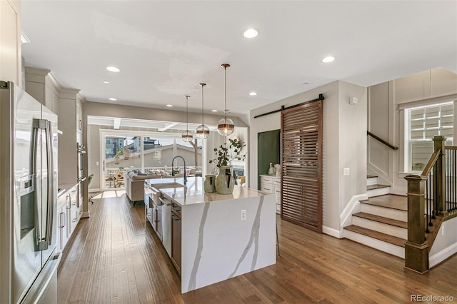 5880 Beeler Ct, Denver, CO 80238 - kitchen with stainless steel fridge, a barn door, dark wood finished floors, a spacious island, and light stone countertops
